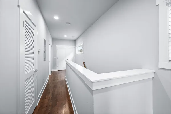 a hallway with white cabinets and wooden floor