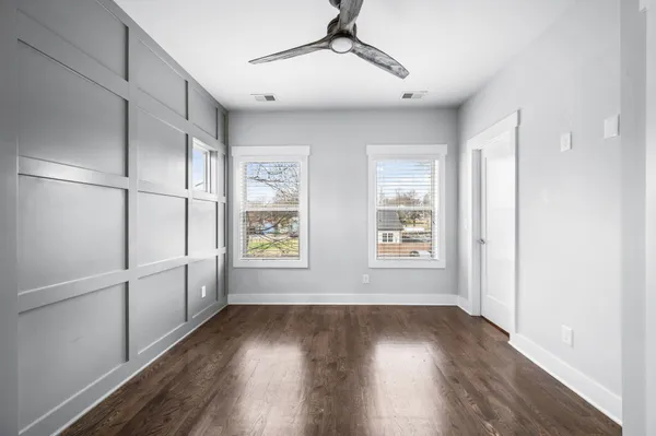 a view of empty room with wooden floor and fan