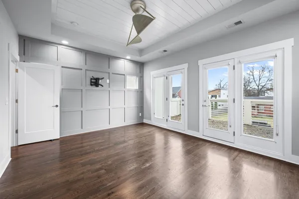 a view of a livingroom with wooden floor a ceiling fan and windows