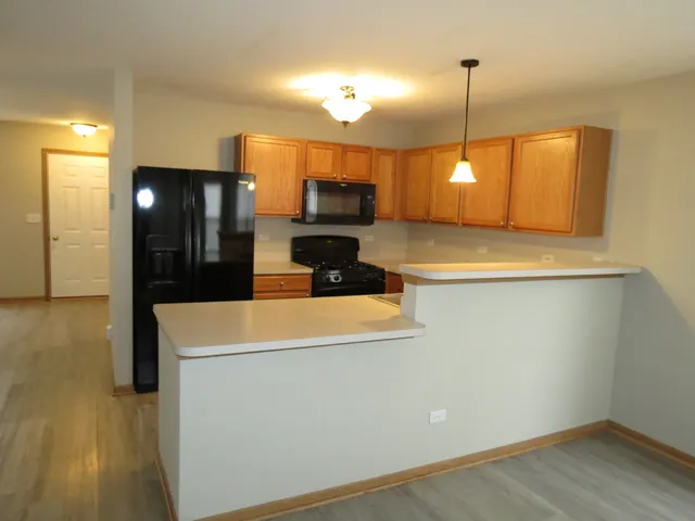 a view of a kitchen with a refrigerator a microwave and wooden floor