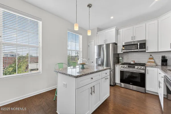 a kitchen with stainless steel appliances kitchen island granite countertop a stove a sink and a refrigerator