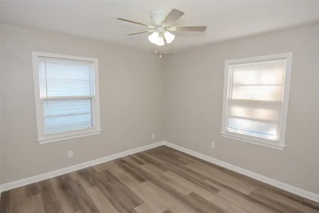 a view of an empty room with a window and a ceiling fan