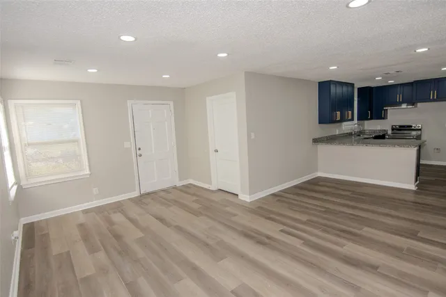 a view of kitchen and empty room with wooden floor and windows