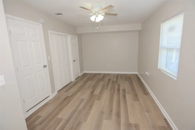 a view of a room with wooden floor and a ceiling fan