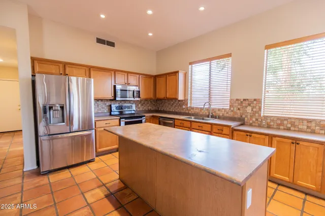 a large kitchen with stainless steel appliances a large counter top a stove a chimney a sink and a refrigerator