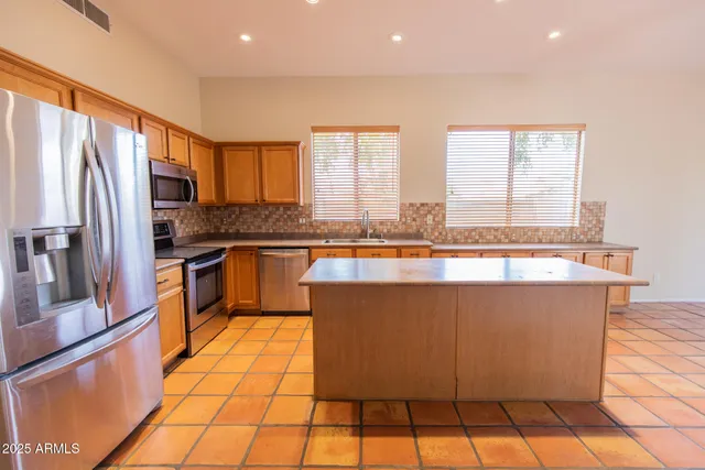 a large kitchen with granite countertop a large counter top stainless steel appliances and cabinets
