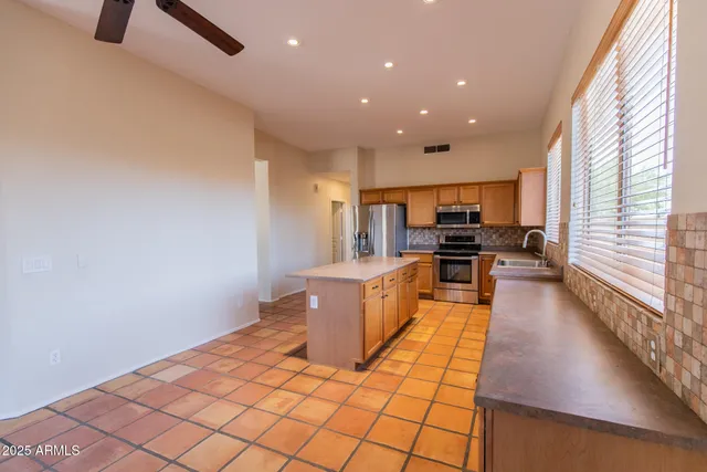 a view of a kitchen with kitchen island granite countertop a refrigerator cabinets and a sink