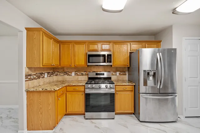 a large kitchen with stainless steel appliances granite countertop a stove refrigerator and a microwave