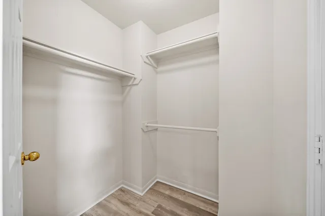 an empty room with wooden floor chandelier fan and windows