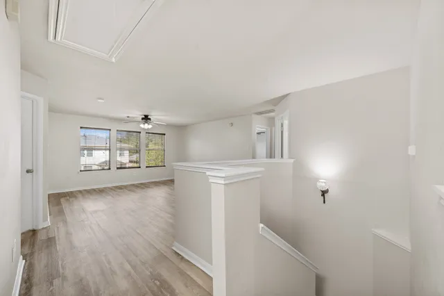 a view of empty room with wooden floor and ceiling fan