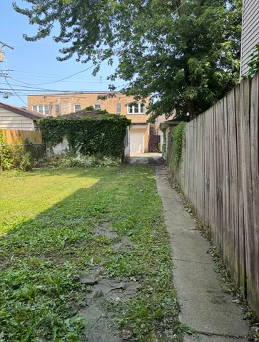 a view of a yard with an tree and wooden fence
