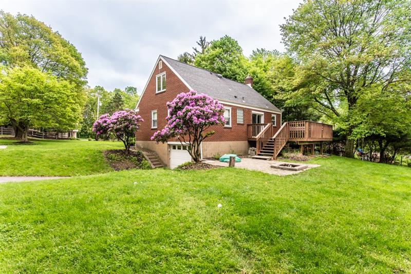 10089 Grubbs Road Wexford, PA 15090 - Photo 25 of 25 Back and side of house showing deck, paver patio with fire pit, driveway/garage. There are stairs on both sides of the driveway for access to front and back yards. There is also a parking pad to left - space for 2 cars.