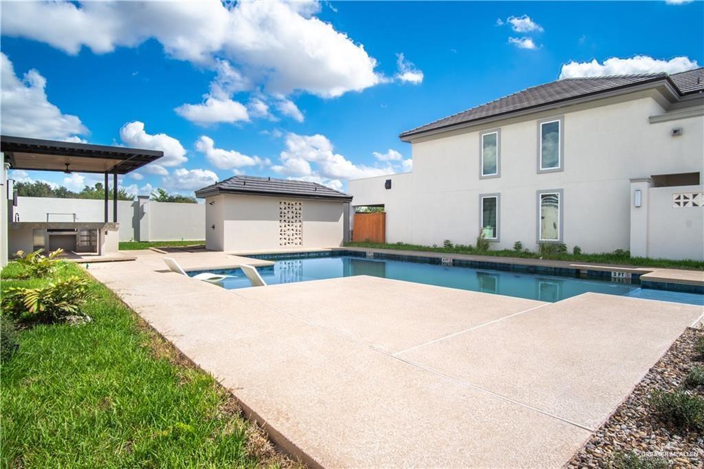 2206 Corales Street Mission, TX 78573 - Photo 21 of 23 Expansive outdoor living area featuring a rectangular swimming pool, concrete decking, an integrated outdoor kitchen with a built-in grill, and a covered patio with a ceiling fan
