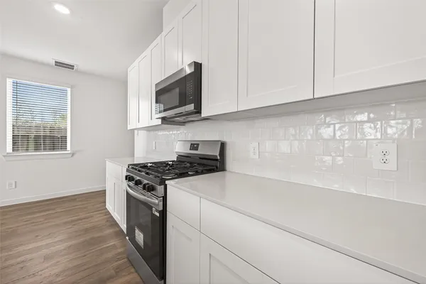 a kitchen with stainless steel appliances white cabinets and a stove top oven