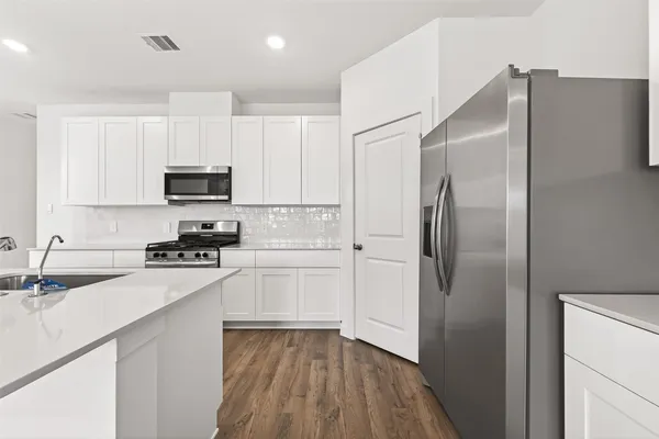 a kitchen with a refrigerator a sink and white cabinets