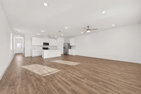 a view of kitchen with kitchen island a sink dishwasher and a stove with wooden floor