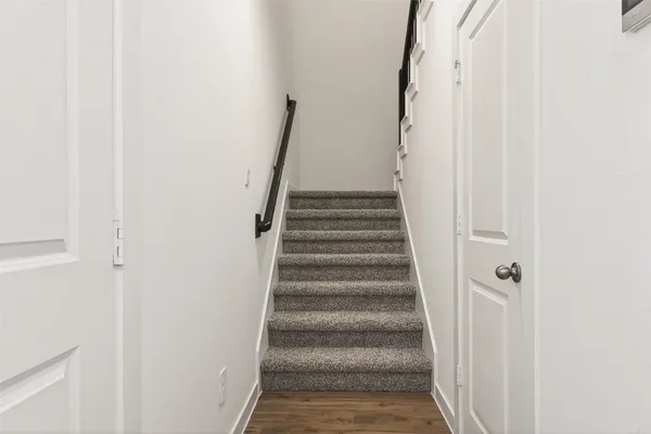 a view of staircase with white walls and white door