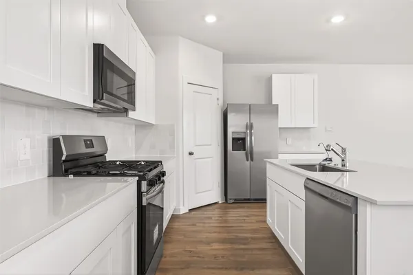 a kitchen with stainless steel appliances a sink stove refrigerator and cabinets