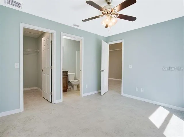 an empty room with closet and a ceiling fan