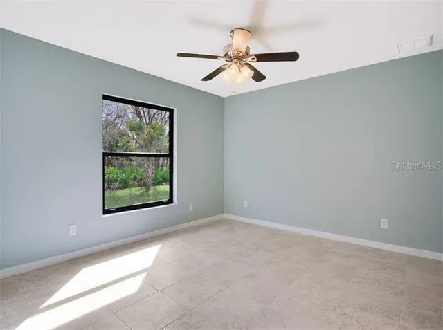 an empty room with windows and fan