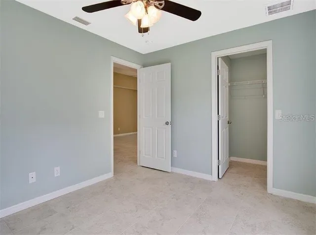 an empty room with a ceiling fan and carpet