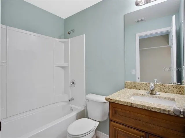 a bathroom with a granite countertop sink a toilet and bathtub