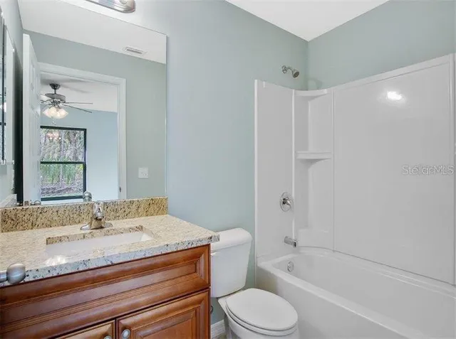 a bathroom with a granite countertop sink a toilet and bathtub