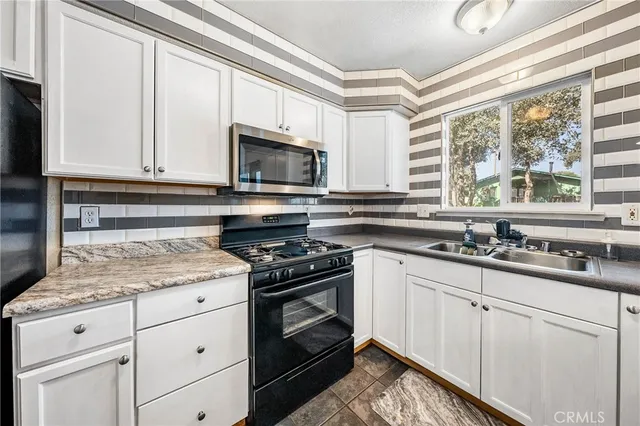 a kitchen with granite countertop a sink cabinets stainless steel appliances and a window