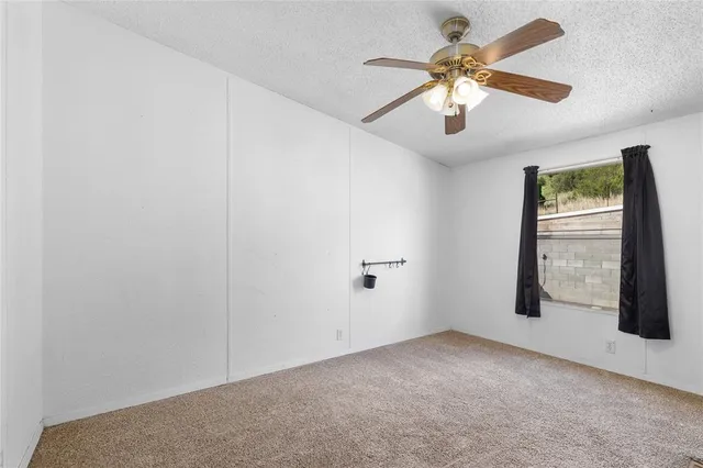 an empty room with chandelier fan and windows