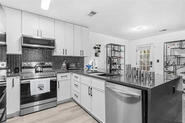 a kitchen with stainless steel appliances granite countertop a stove sink and cabinets