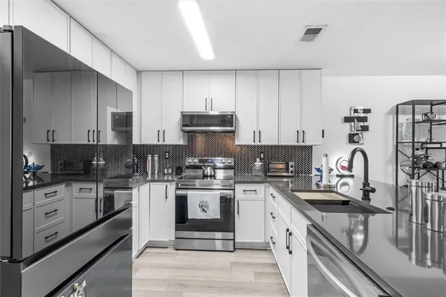 a kitchen with stainless steel appliances granite countertop a stove top oven a sink dishwasher and a refrigerator with wooden cabinets