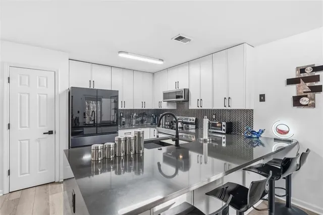 a kitchen with stainless steel appliances granite countertop a dining table chairs and granite counter tops