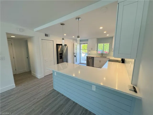 a kitchen with stainless steel appliances white cabinets sink and a window