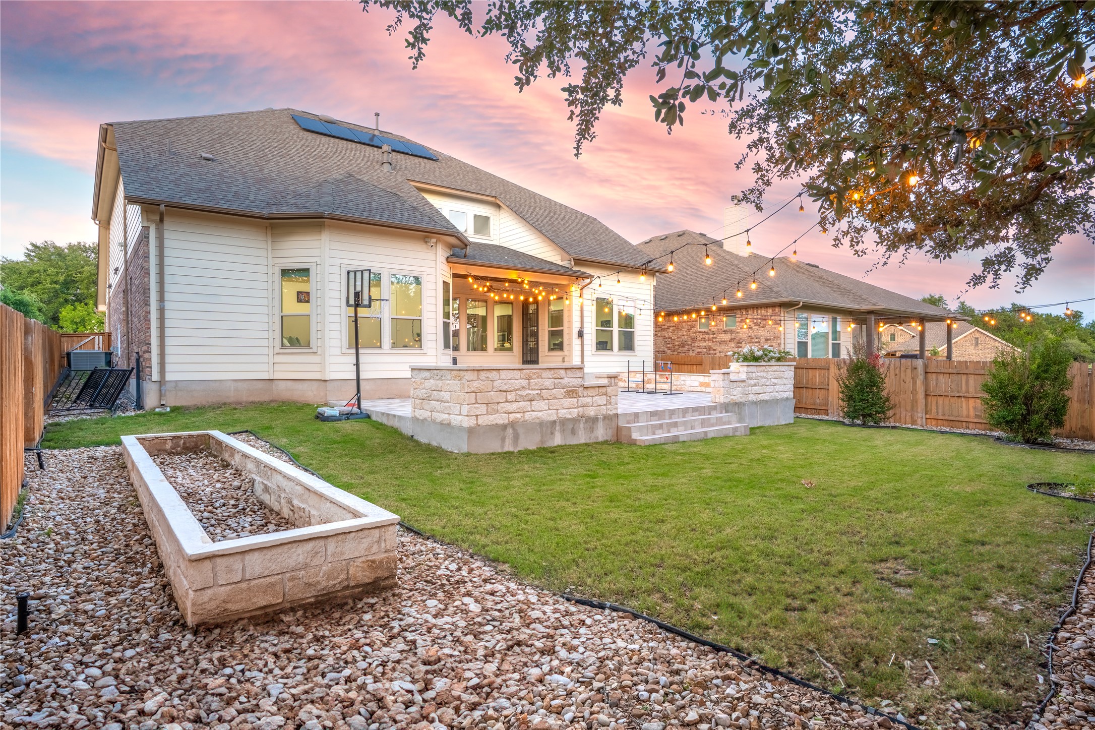 228 Lockhart Loop Georgetown, TX 78628 - Photo 31 of 37 Rear view of house with a patio, a fenced backyard, roof with shingles, roof mounted solar panels, and a garden