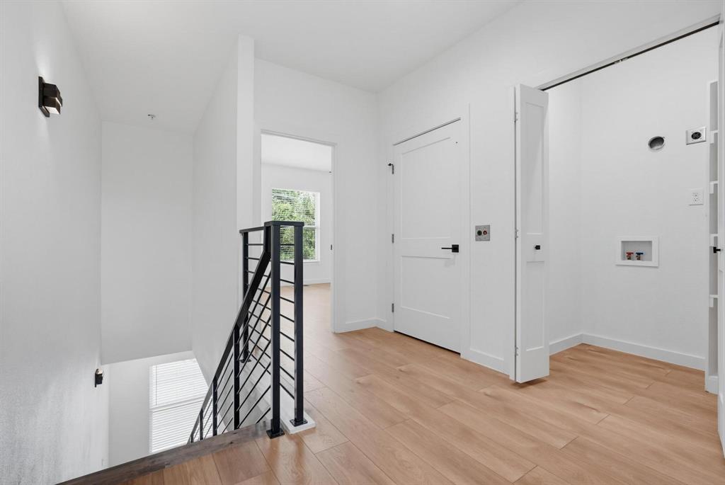 504 South O Connor Road Irving, TX 75060 - Photo 11 of 23 Contemporary interior landing featuring wood-finish flooring, a modern black metal stair railing, and crisp white walls
