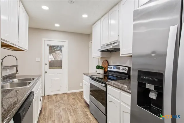 a kitchen with stainless steel appliances granite countertop a sink stove and refrigerator