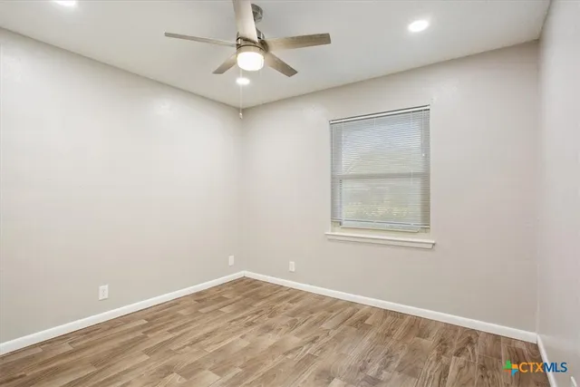 an empty room with a window and a fan