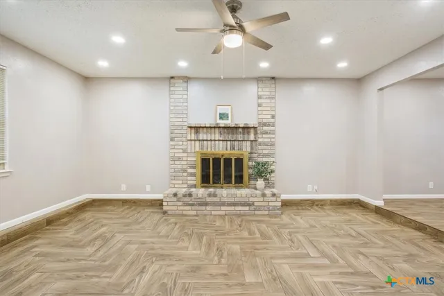 a view of an empty room with a fireplace and a window