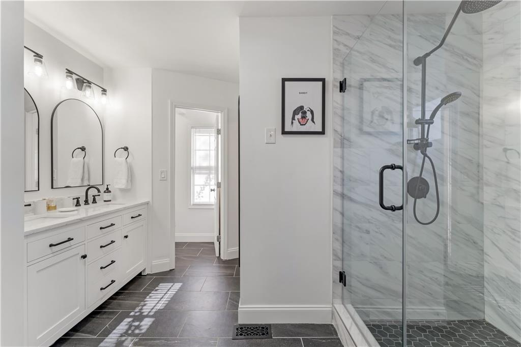 777 Forrest Street Northwest Atlanta, GA 30318 - Photo 19 of 35 a bathroom with a double vanity sink a mirror a glass door a shower and a bathtub