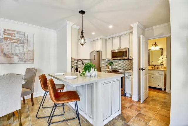 a kitchen with stainless steel appliances kitchen island granite countertop a sink and a refrigerator