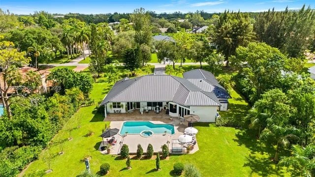 an aerial view of residential houses with outdoor space and trees