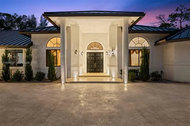 a view of a house with large windows and a wooden fence