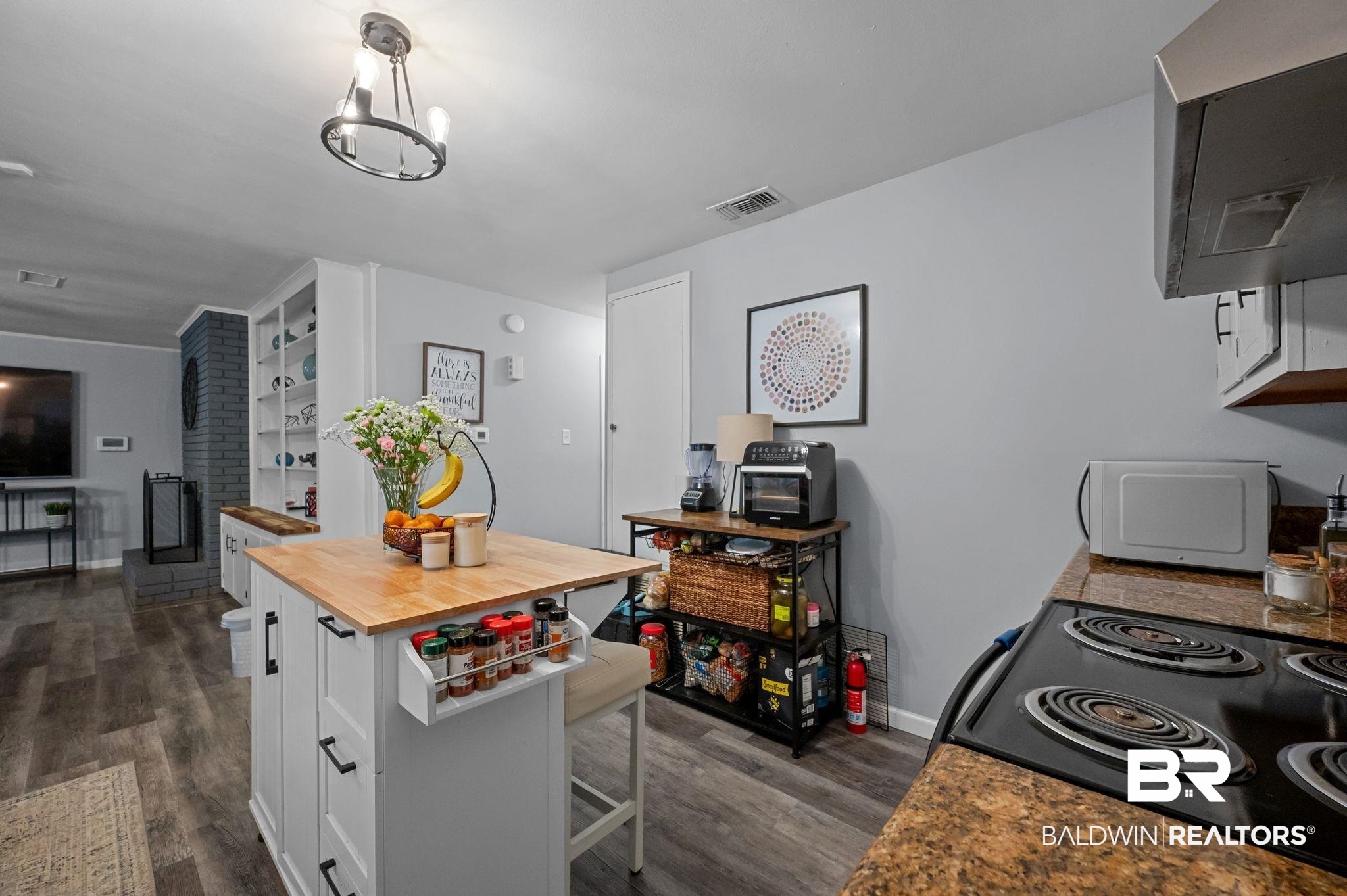 4724 Wicker Way Mobile, AL 36609 - Photo 11 of 36 Kitchen featuring a butcher block island with built-in storage, wood-finish flooring, light gray wall tones, and a black cooktop with granite-style countertops