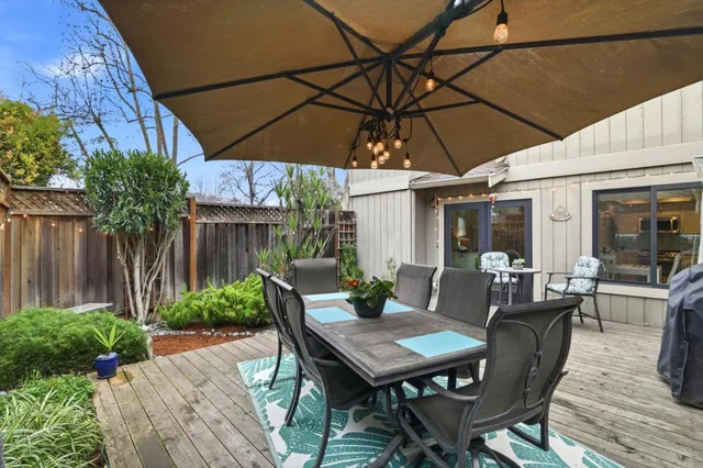 a patio with wooden floor a yard a table and chairs