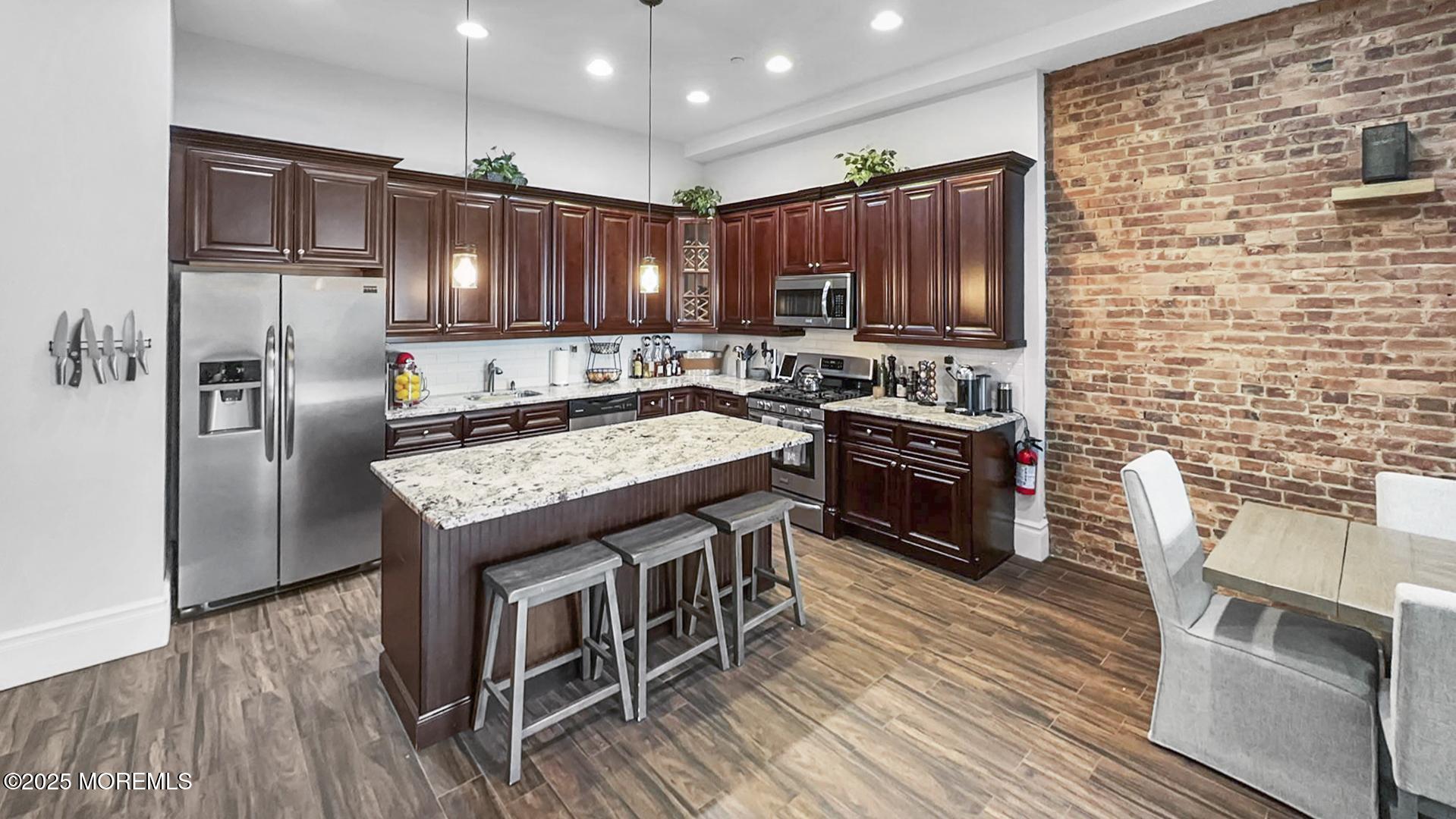 a kitchen with granite countertop a stove a sink dishwasher a refrigerator and wooden floor