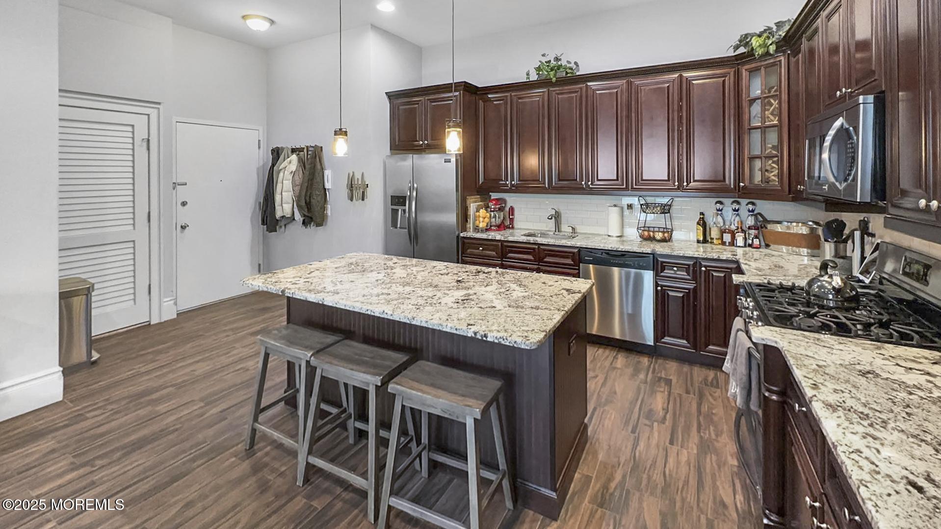 18 Broad Street, Unit 2F Red Bank, NJ 07701 - Photo 4 of 13 a kitchen with granite countertop wooden floors wooden cabinets a center island and stainless steel appliances
