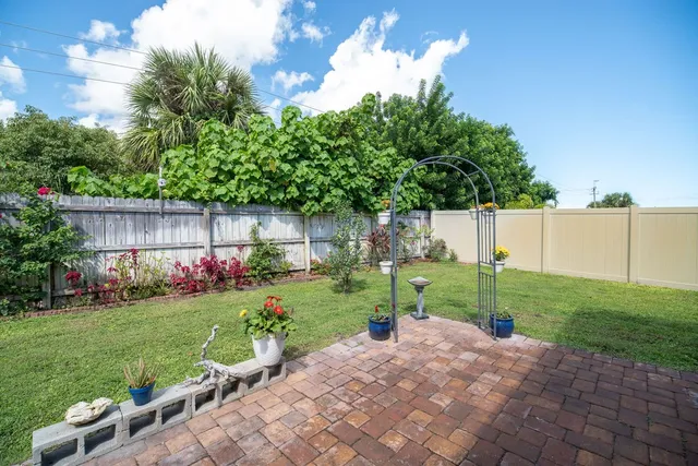 a view of a back yard with flower plants and wooden fence