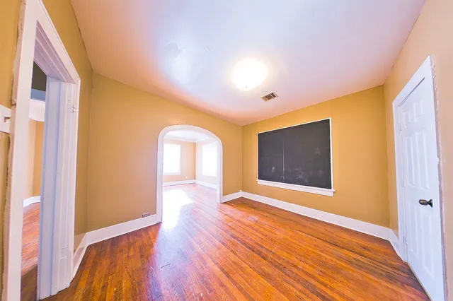 a view of an empty room with wooden floor and a window