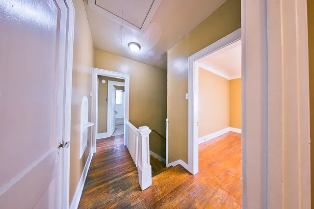 a view of a hallway with wooden floor and staircase