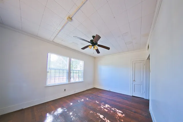 an empty room with windows and ceiling fan